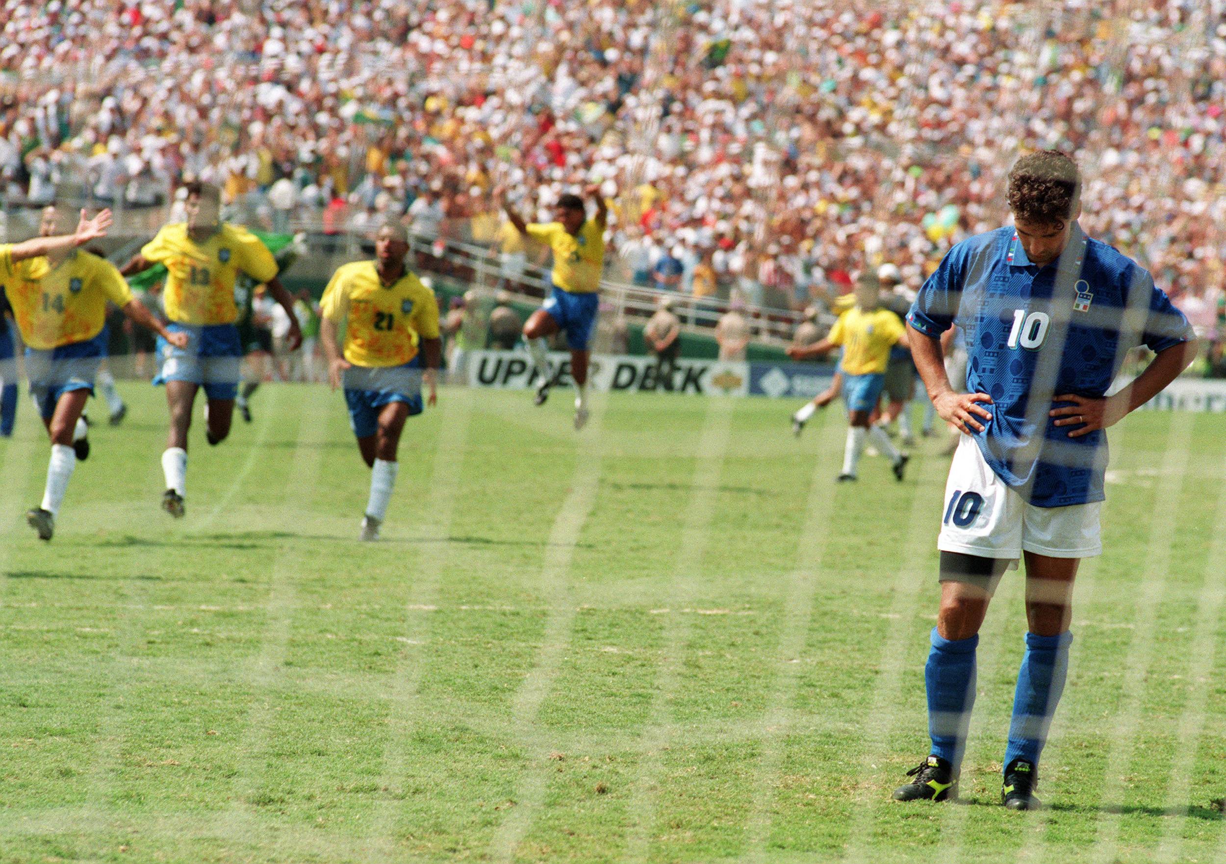 LOS ANGELES, UNITED STATES:  Brazilian players run to join their teammates as Italian midfielder Roberto Baggio bows his head after he missed his penalty kick giving Brazil a 3-2 victory in the shoot-out session (0-0 after extra time) at the end of the World Cup final, 17 July 1994 at the Rose Bowl in Pasadena. Brazil won its fourth World Cup title after 1958, 1962 and 1970.   AFP PHOTO/OMAR TORRES (Photo credit should read OMAR TORRES/AFP/Getty Images)