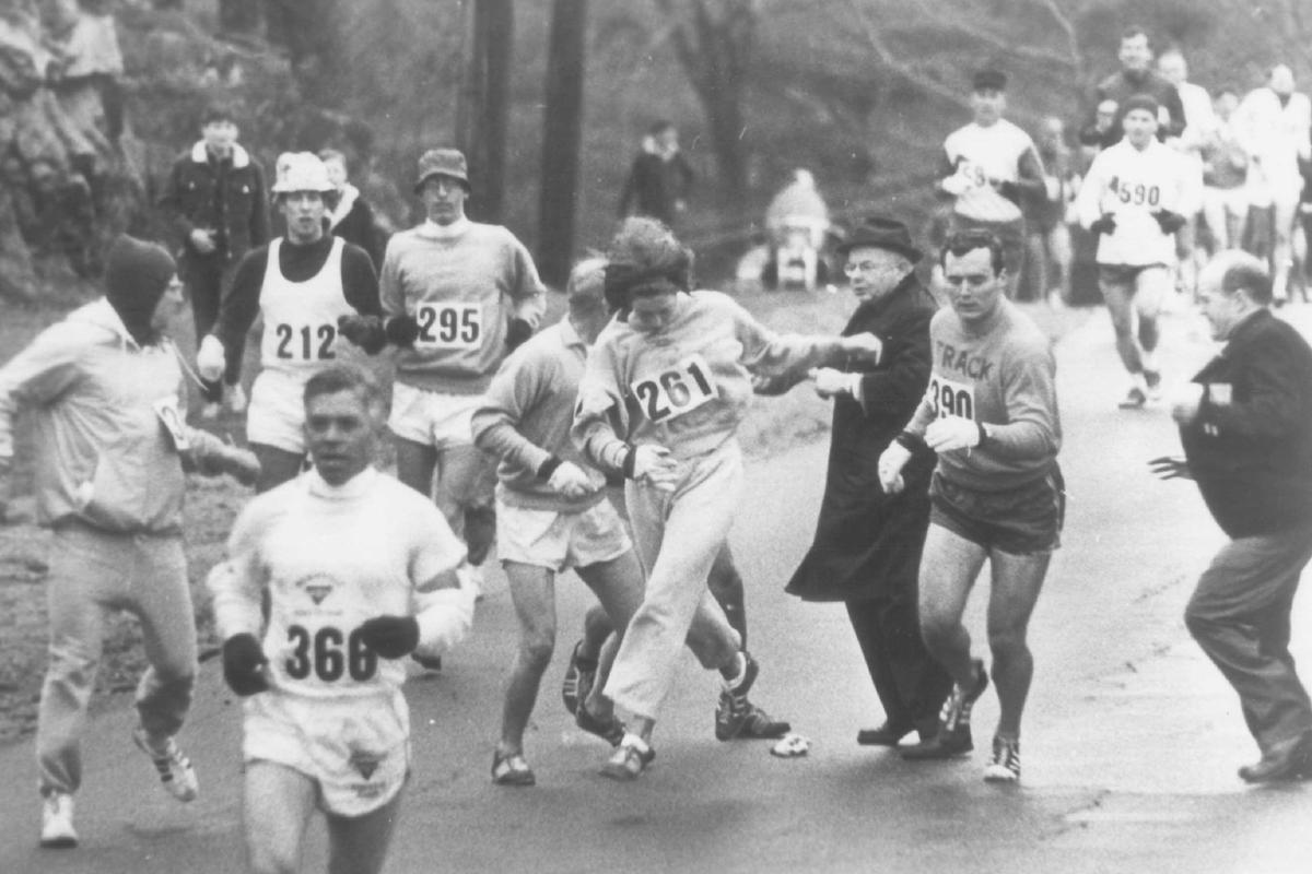 Kathy Switzer, one of two women in the normally an-male Boston marathon in 1967, evades Marathon Director Bill Clooney (in dark suit), who attempted to stop her from running. Ms. Switzer is among the co-anchor persons of the WGBH production, THE BOSTON MARATHON, _ at _ on Channel _.